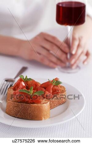 Stock Photograph - Bruschetta and hand holding glass of red wine. Fotosearch