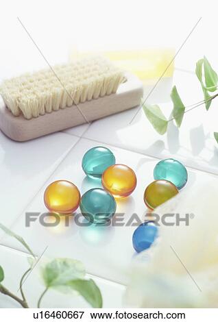Stock Photo - Brush and bath beads on tile, close up. Fotosearch