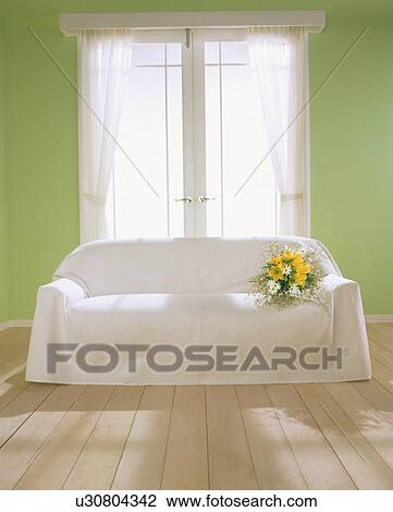 Stock Image - Bunch of flowers on white sofa near doors. Fotosearch