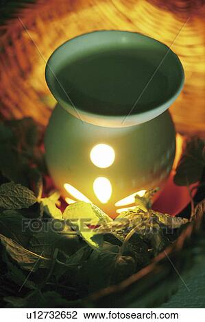 Stock Image - Burning aromatherapy candle in burner. Fotosearch