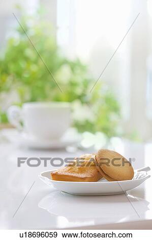 Cakes on plate next to coffee cup View Large Photo Image Stock Photo - Cakes on plate next to coffee cup. Fotosearch