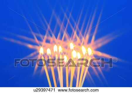 Stock Image - Candles burning against blue background. Fotosearch