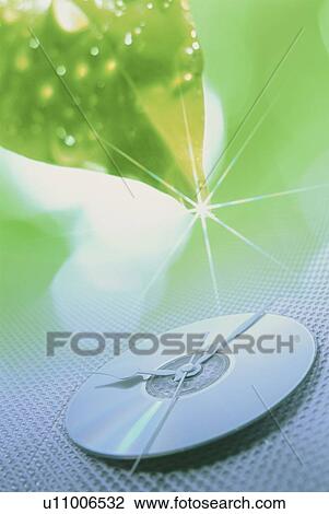 Stock Image - CD clock and dew covered leaf. Fotosearch
