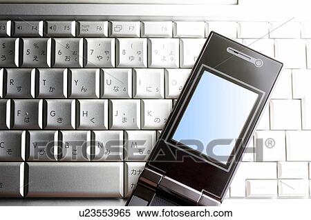 Stock Photography - Cell phone on laptop keyboard. Fotosearch