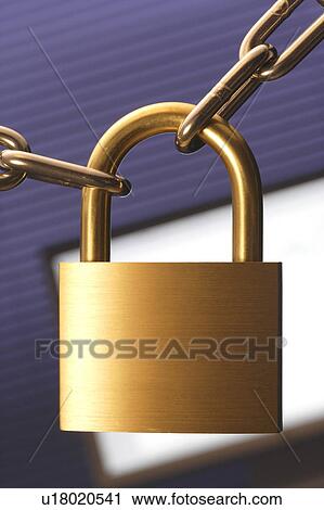 Stock Image - Chain and padlock with computer monitor in background, close up. Fotosearch