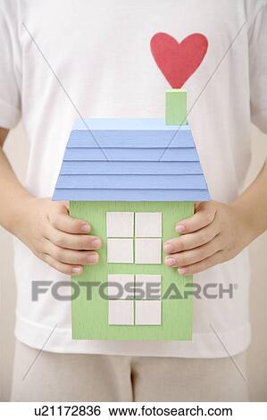 Stock Photograph - Child holding a house with heart shape. Fotosearch