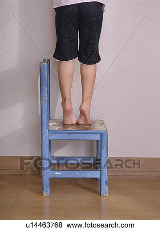 Stock Photo - Child standing and reaching out on chair. Fotosearch