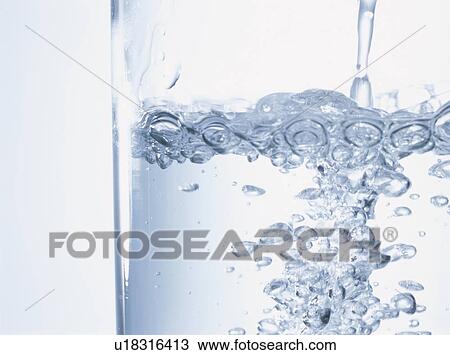 Stock Image - Close-up of water being poured into glass. Fotosearch