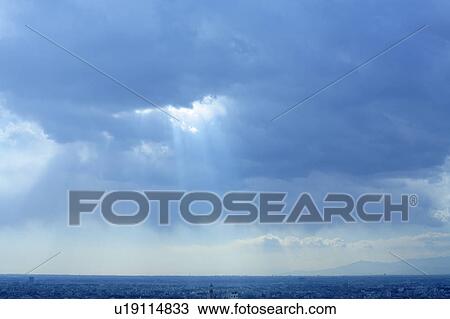 Stock Image - Clouds and sunbeams over city, Tokyo prefecture, Japan. Fotosearch
