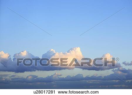Stock Image - Clouds in blue sky, blue background. Fotosearch
