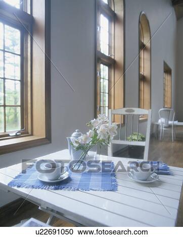 Stock Image - Coffee and flowers on table by window. Fotosearch