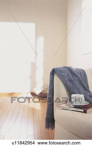 Picture - Coffee cup and scarf on armchair in sunny room. Fotosearch