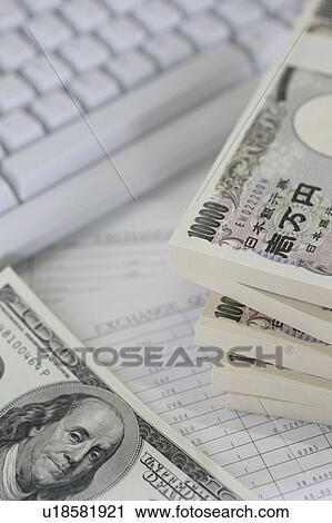 Stock Image - Computer keyboard and bundles of paper currencies . Fotosearch
