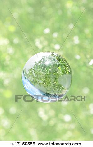 Stock Photography - Crystal globe floating over grass and flowers. Fotosearch