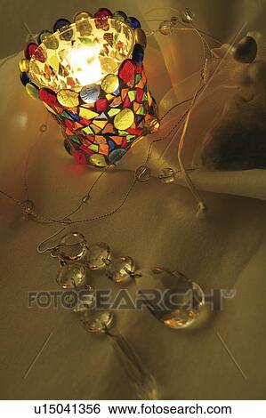 Stock Photograph - Crystal jewellery and a colourful candle. Fotosearch