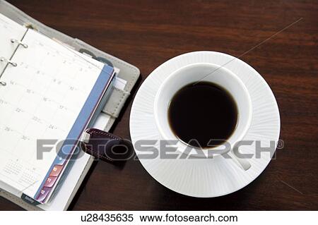 Stock Photography - Cup of coffee next to a diary. Fotosearch