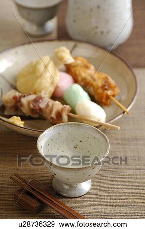 Stock Photo - Cup of Sake and plate of skewered fish balls. Fotosearch
