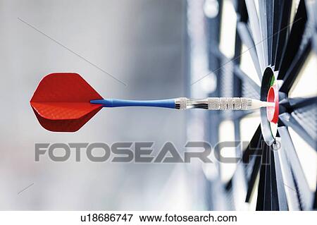 Stock Photo - Dart and dartboard, dart in bull's-eye, close up. Fotosearch