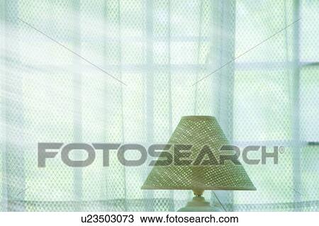 Stock Image - Desk lamp by window with green curtains. Fotosearch