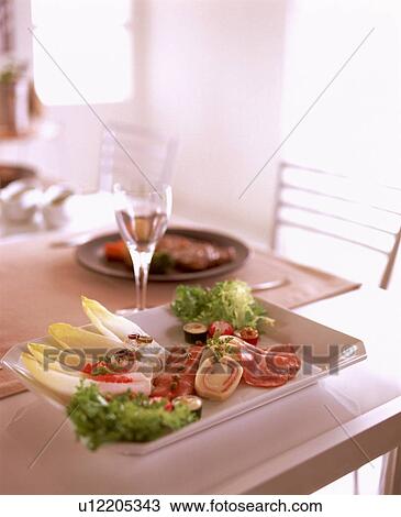 Stock Image - Dish of appetizers and wineglass on table. Fotosearch