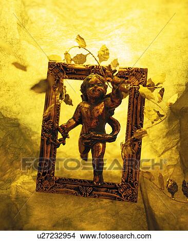 Picture - Figurine of angel in picture frame, colored background. Fotosearch