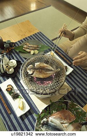 Stock Image - Fish being cooked on charcoal brazier. Fotosearch