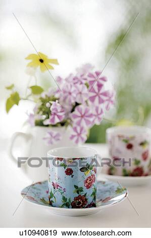 Floral patterned teacups and saucers with flowers in a jug View Large Photo Image Stock Photo - Floral patterned teacups and saucers with flowers in a jug. Fotosearch