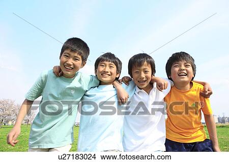 Picture - Four boys laughing with arms around each other on field. Futako-tamagawa, Setagaya-ku, Tokyo Prefecture, Japan. Fotosearch