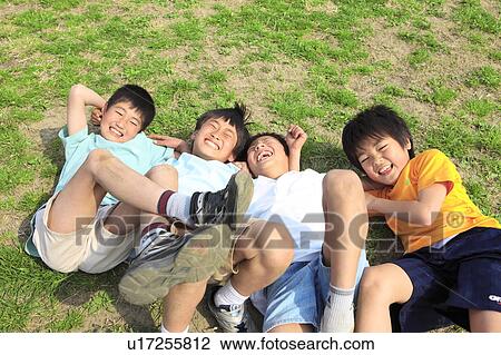 Stock Image - Four boys lying on field laughing. Futako-tamagawa, Setagaya-ku, Tokyo Prefecture, Japan. Fotosearch