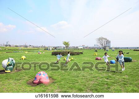 Stock Photo - Four children running on field in playground. Futako-tamagawa, Setagaya-ku, Tokyo Prefecture, Japan. Fotosearch