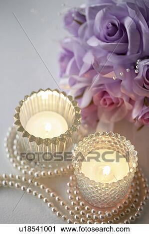 Stock Image - Glass candle holders with pearls and corsage. Fotosearch