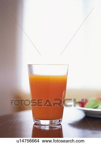Picture - Glass of carrot juice on table. Fotosearch