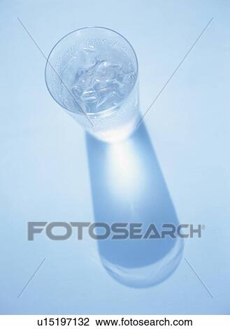 Stock Image - Glass of water being reflected on blue background. Fotosearch