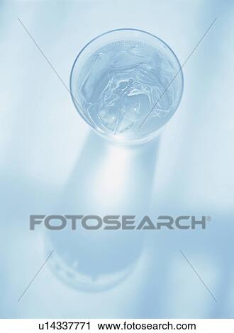 Stock Image - Glass of water, blue background. Fotosearch