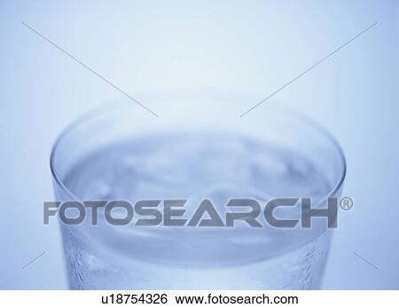 Stock Photograph - Glass of water, close up, blue background. Fotosearch