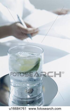 Glass of water with office worker in the background View Large Photo Image Stock Image - Glass of water with office worker in the background. Fotosearch