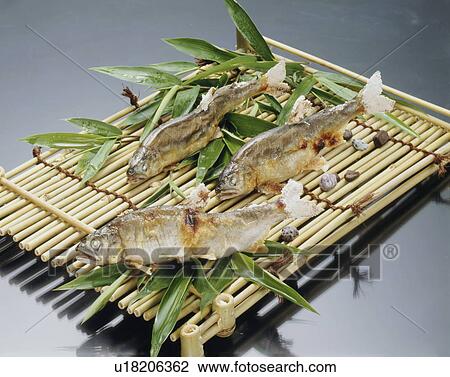 Stock Image - Grilled fish on bamboo tray, black background. Fotosearch