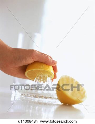 Picture - Hand juicing lemon half on juicer. Fotosearch