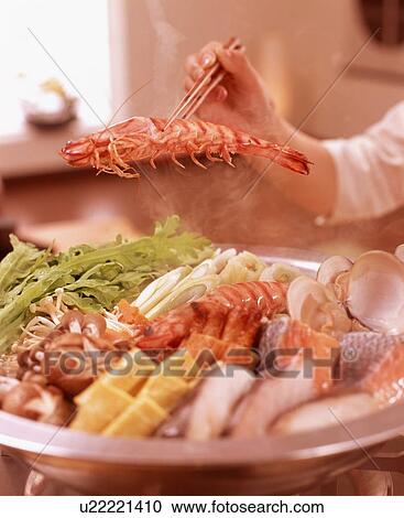 Stock Image - Hand serving seafood from dish with chopsticks. Fotosearch