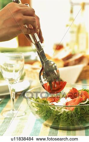 Picture - Hands serving tomato and lettuce salad. Fotosearch