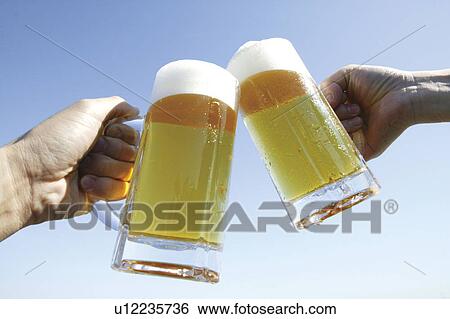 Hands toasting with glass of beer against blue sky, blue background View Large Photo Image Stock Photograph - Hands toasting with glass of beer against blue sky, blue background. Fotosearch