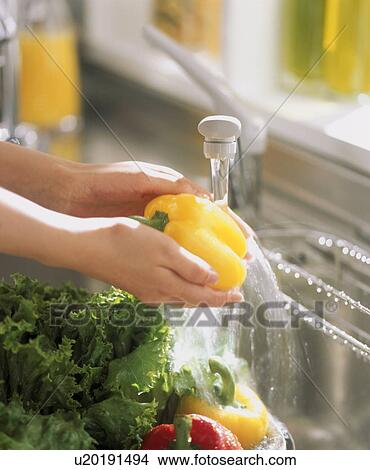 Picture - Hands washing yellow capsicum. Fotosearch