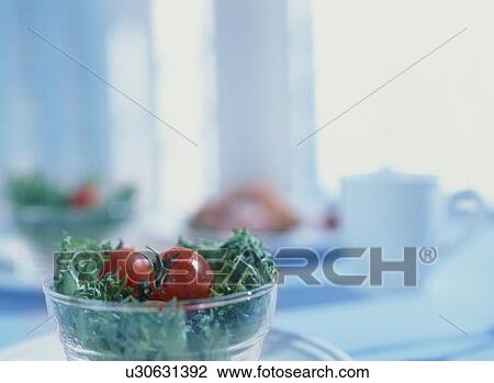 Stock Image - Healthy salad with tomatoes and green leafy vegetables. Fotosearch
