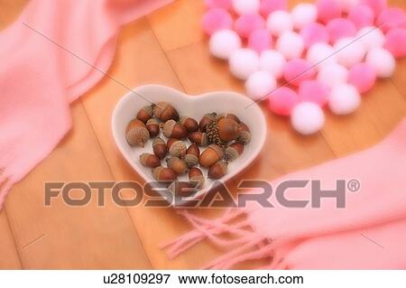 Stock Photo - Heart shaped bowl with acorns next to pink scarf. Fotosearch