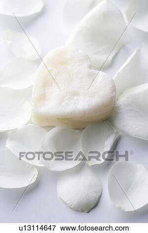 Stock Photo - Heart shaped soap amongst white petals. Fotosearch