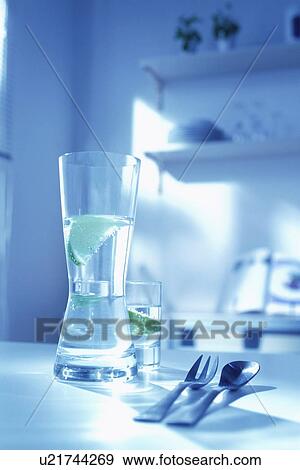 Stock Photo - Jug and glass of water on table next to fork and spoon. Fotosearch