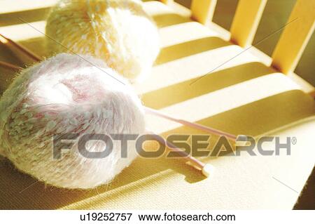 Stock Photo - Knitting needles and yarn balls on chair, close up. Fotosearch