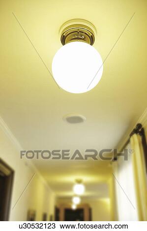 Stock Image - Light bulb on ceiling illuminated. Fotosearch