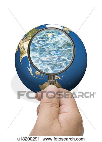 Stock Image - Man looking into globe though magnifying glass. Fotosearch