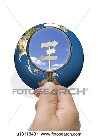 Stock Photo - Man looking into globe though magnifying glass. Fotosearch